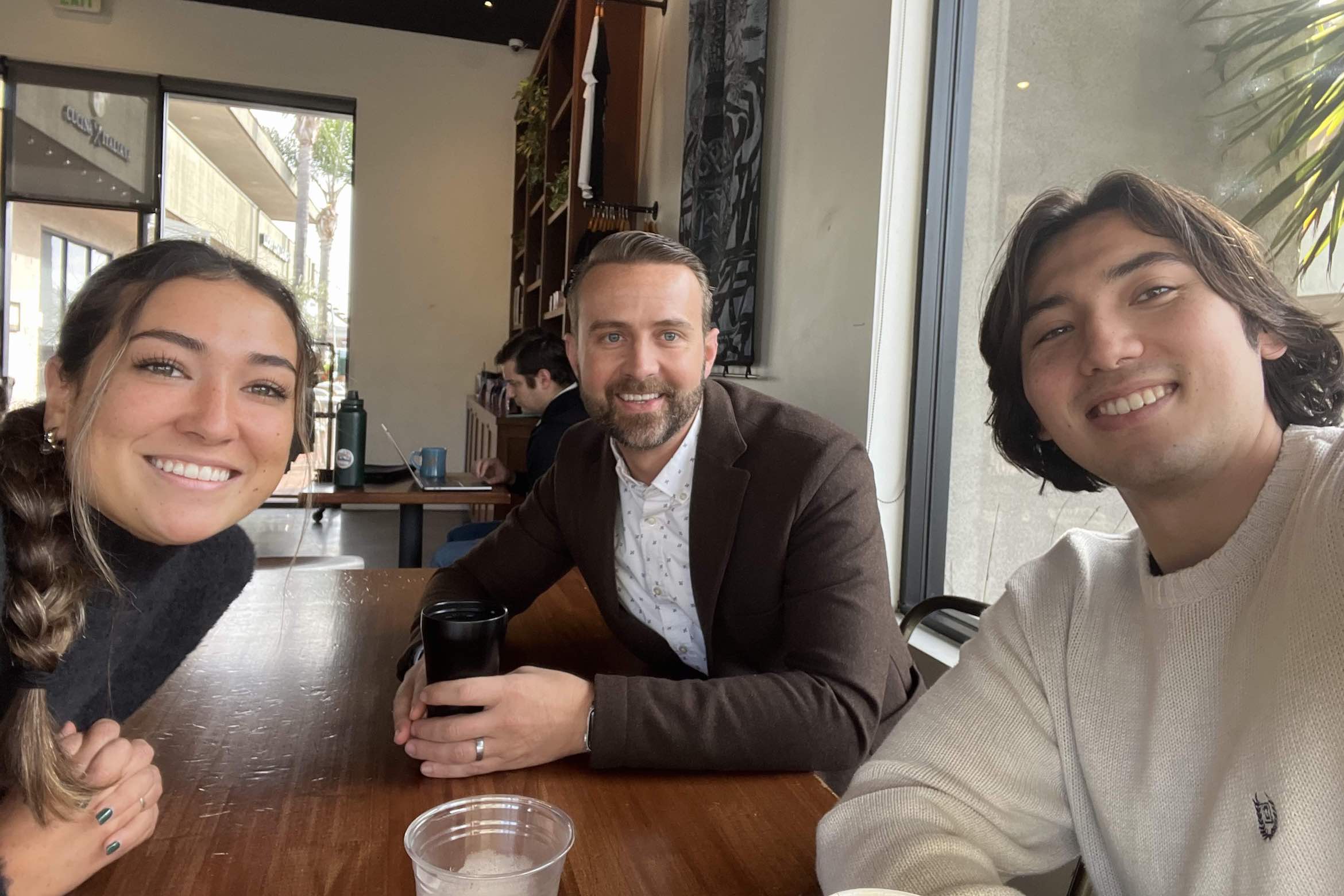 student seated at table with two mentors